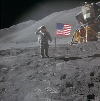 un astronauta con un voluminoso traje espacial blanco planta una bandera estadounidense en la polvorienta superficie gris de la luna