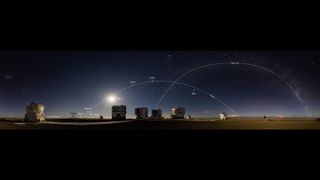 Se pueden ver muchos puntos brillantes en un cielo nocturno estrellado sobre un grupo de edificios en un desierto