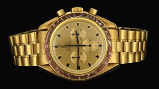 Un reloj de pulsera dorado con característica de cronógrafo