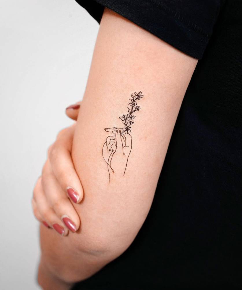 Fine Line Hand Holding Flower Tattoo On The Tricep. 1000_x_837_jpg
