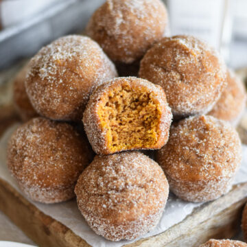 A pile of pumpkin churro mini muffins on a wooden tray.