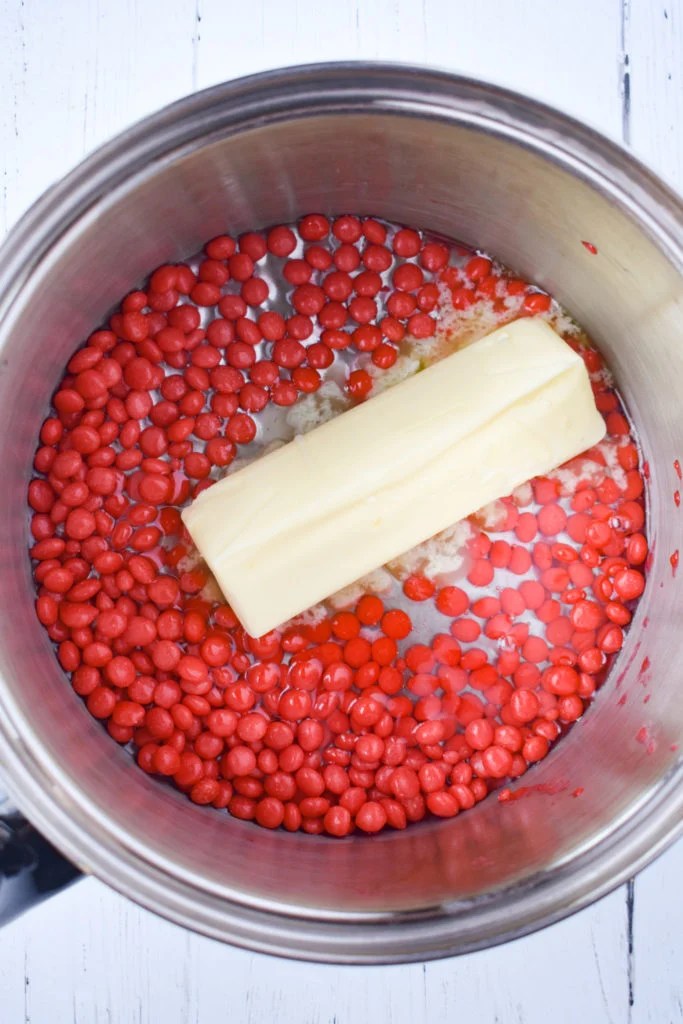 butter, corn syrup, and red hot candies in a stainless steel pot.