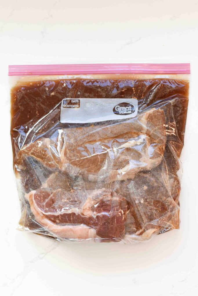 Steaks in a marinade in a large ziplock bag.