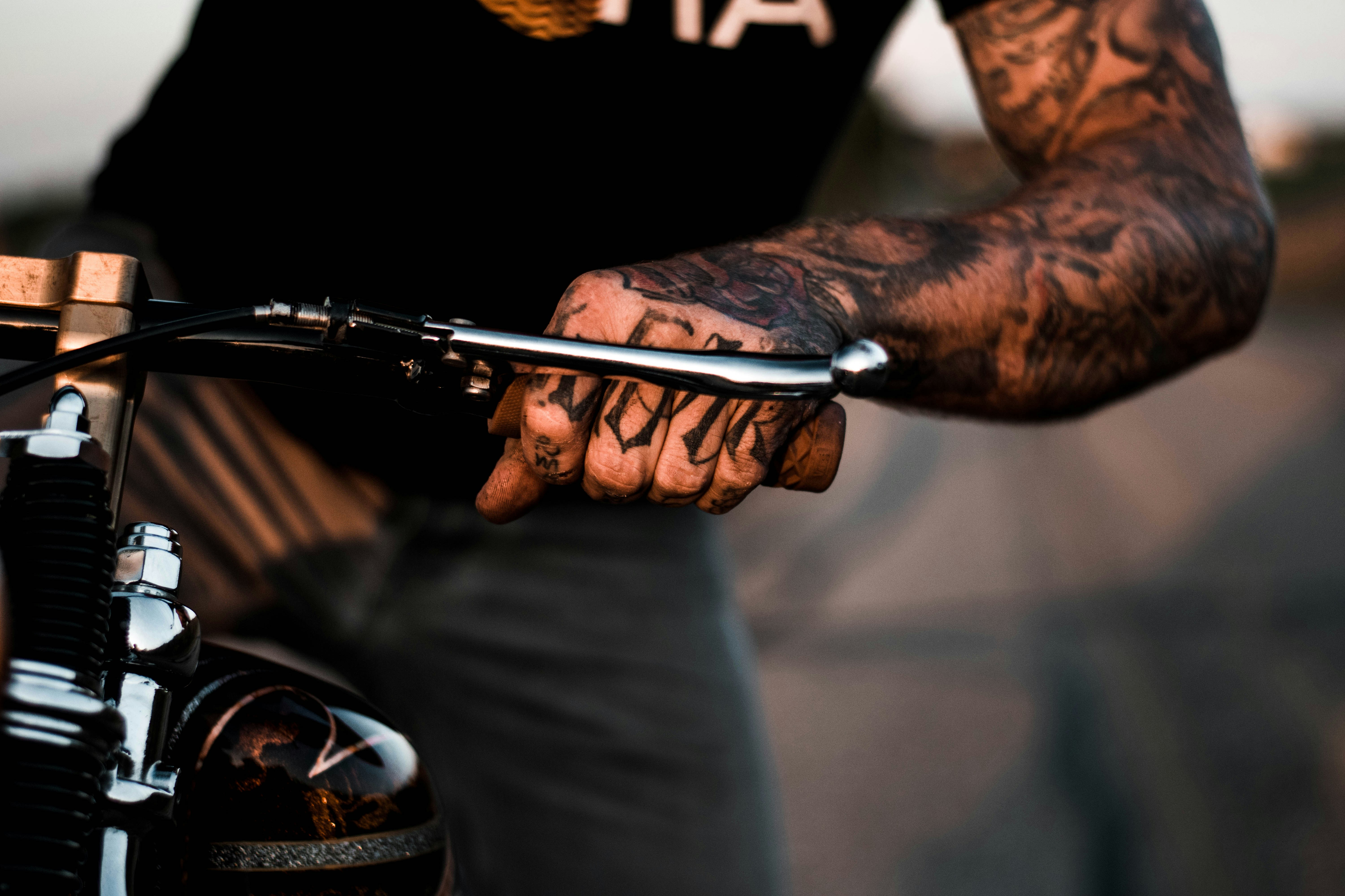 Person With Tattoos On Arm Riding Motorcycle Photo – Free Skin Image On Unsplash 667_x_1000_jpg