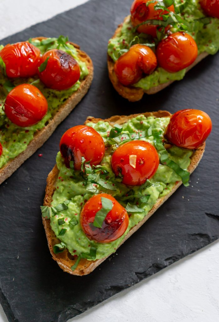 three tomato crostini on a black slate