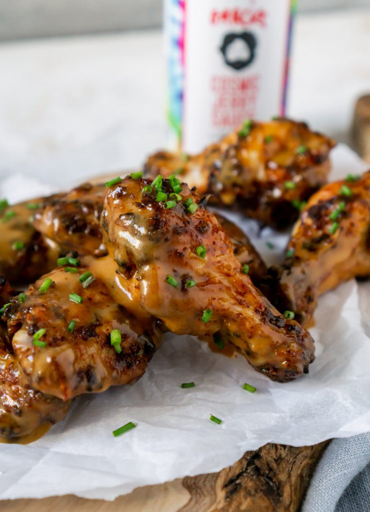 air fryer wings on parchment paper with sauce in the background