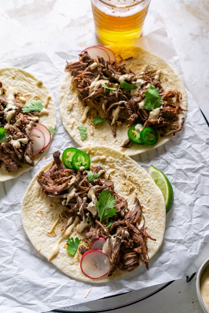 three barbacoa tacos with beer