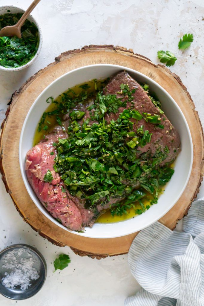 steak marinating in a white bowl