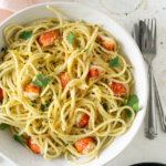 lobster pasta in a white bowl with a silver fork and wine