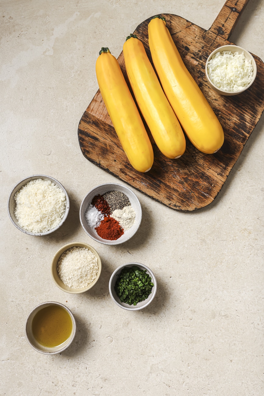 yellow squash, parmesan cheese, spices, parsley, and olive oil in small ingredient bowls.