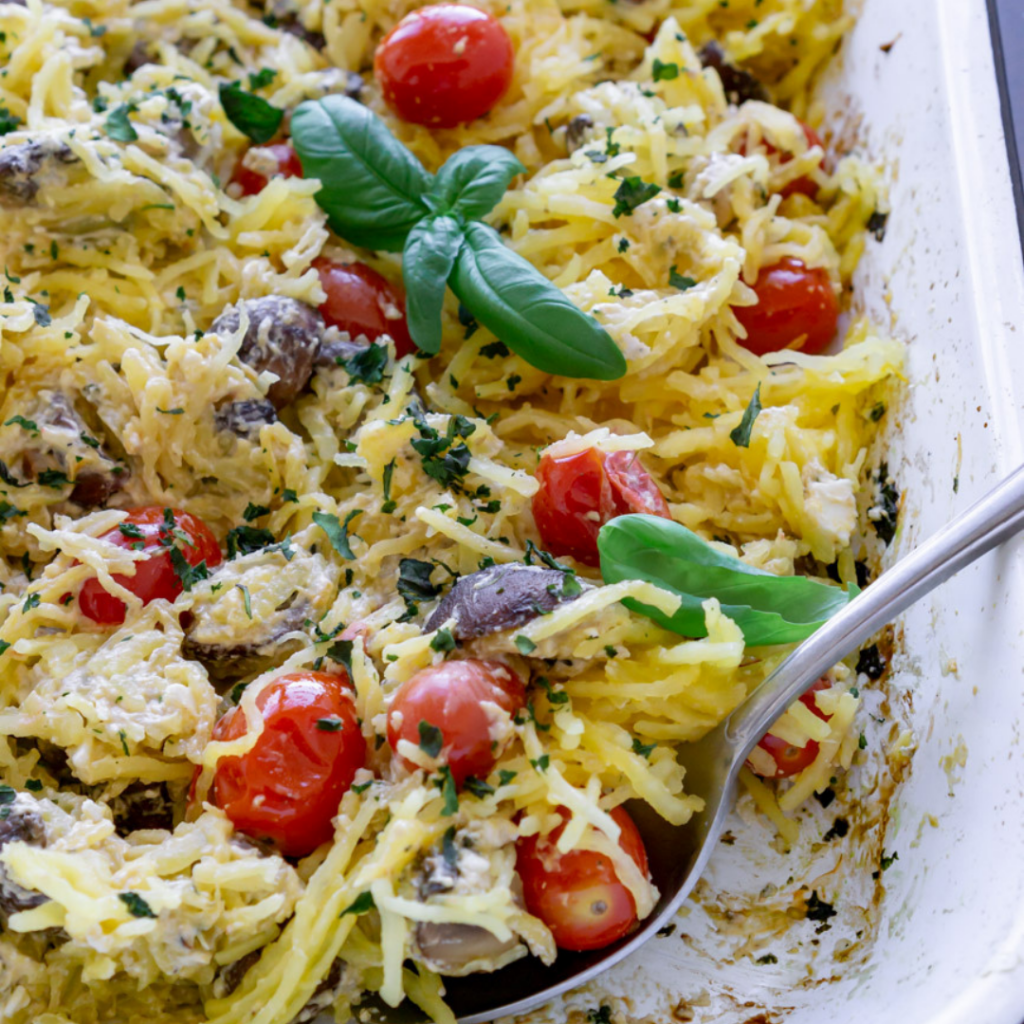 baked spaghetti squash with tomatoes, mushrooms, and feta cheese in a white dish