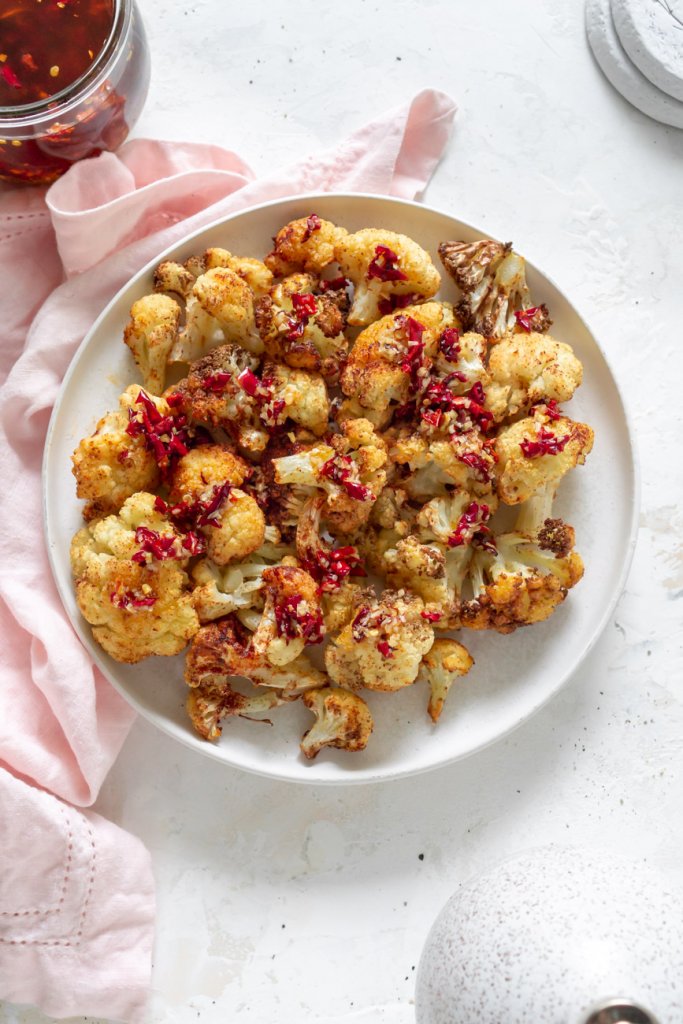 air fryer cauliflower on a plate with chili garlic sauce