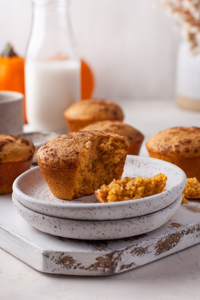 a pumpkin muffin with a bite taken on two white plates