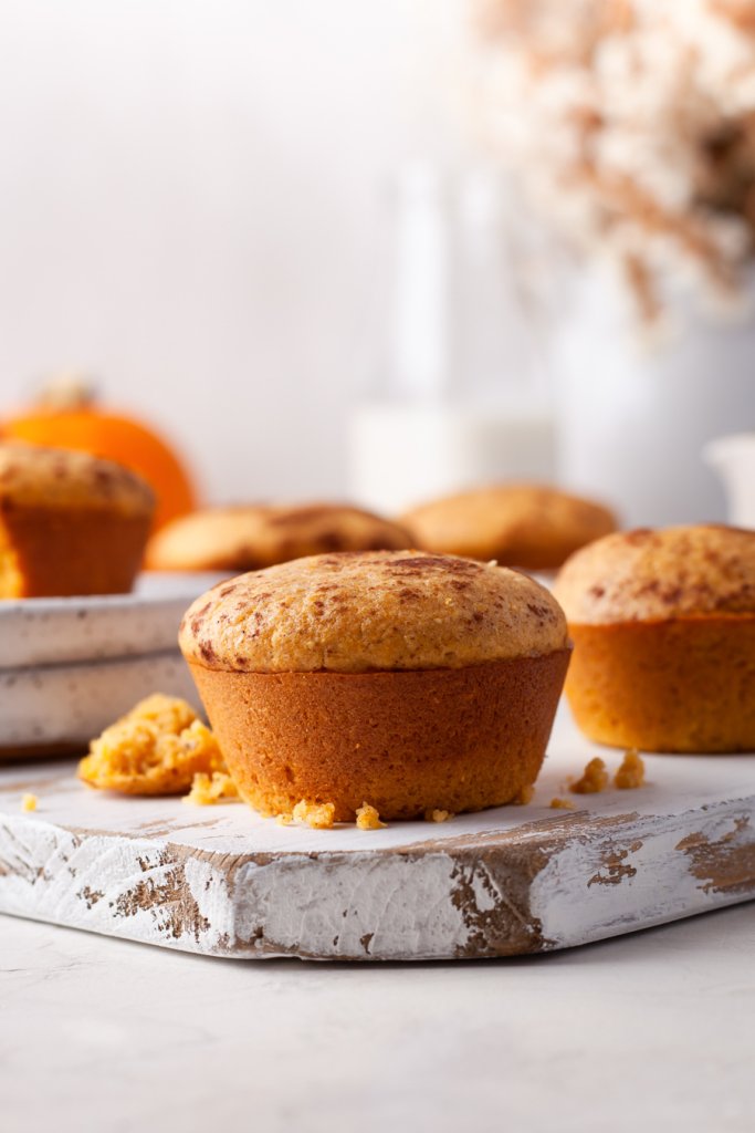 pumpkin cornbread muffin on a wood board with flowers behind