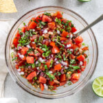 homemade chunky salsa in a glass mixing bowl with a spoon