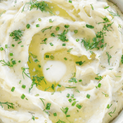 Slow cooker mashed potatoes garnished with dill and green onions.