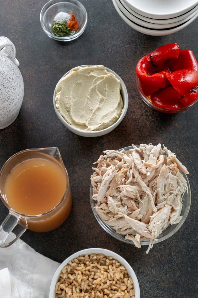 shredded chicken, hummus, roasted peppers, broth, and rice in small ingredient bowls