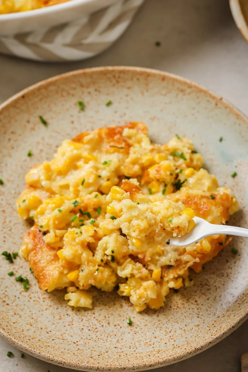a fork lifting a bite of corn casserole from a plate