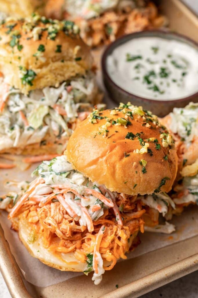 close up of a buffalo chicken slider on a sheet pan with ranch behind it