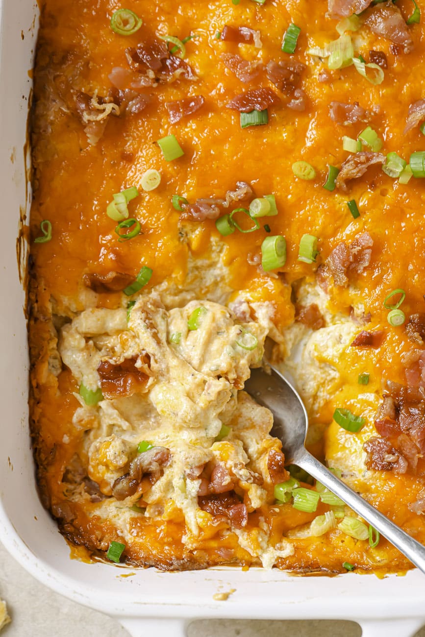 crack chicken dip in a white baking dish with a silver serving spoon