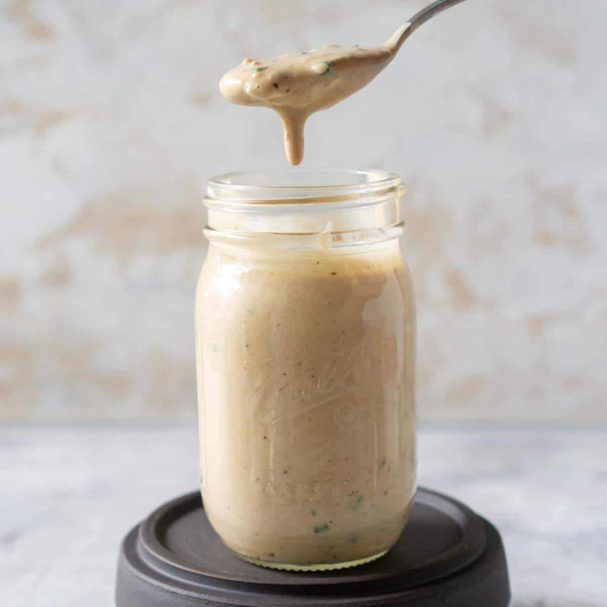 Spooning remoulade sauce out of a mason jar.