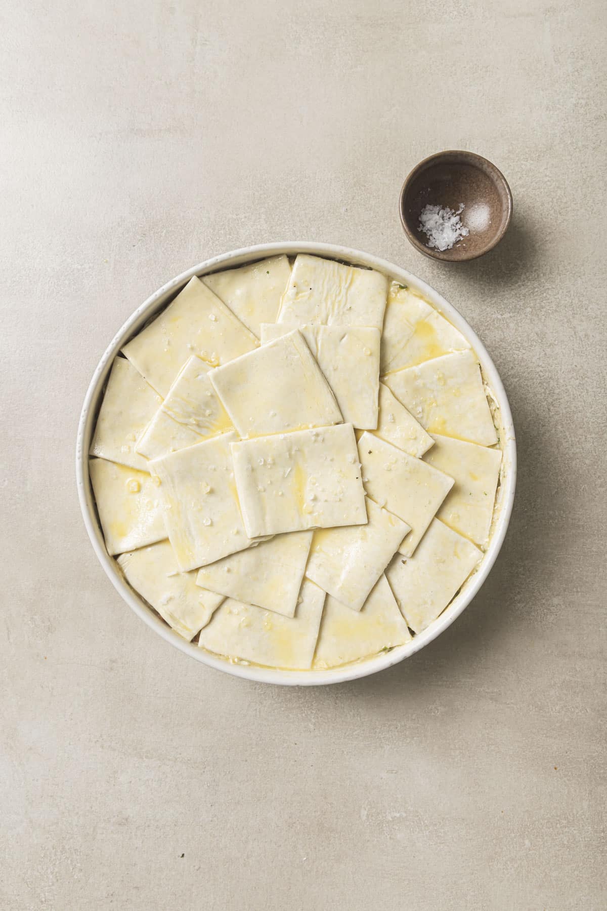 Pieces of puff pastry dough layered over pot pie mixture.