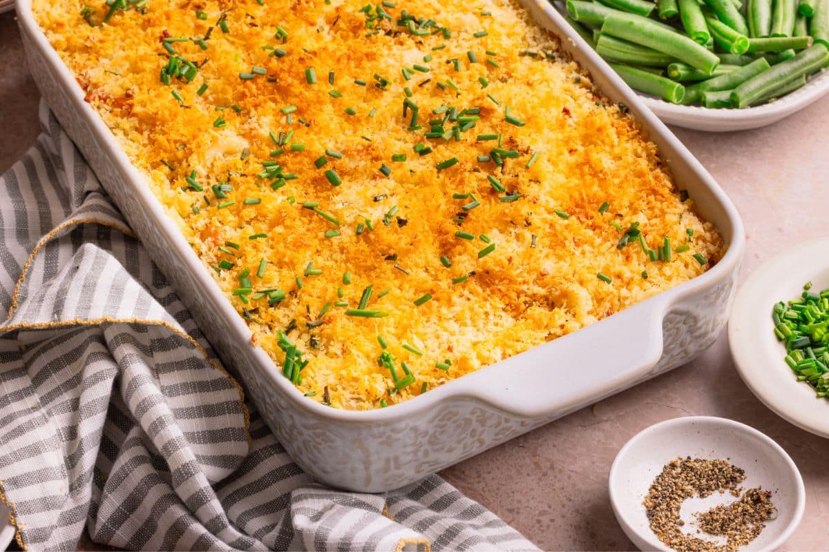 A cheesy mashed potato casserole with a panko topping in a white baking dish.
