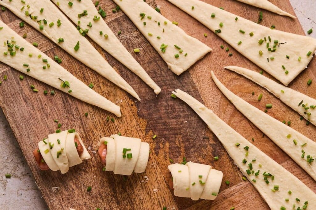 Wrapping little smokies in crescent roll dough.