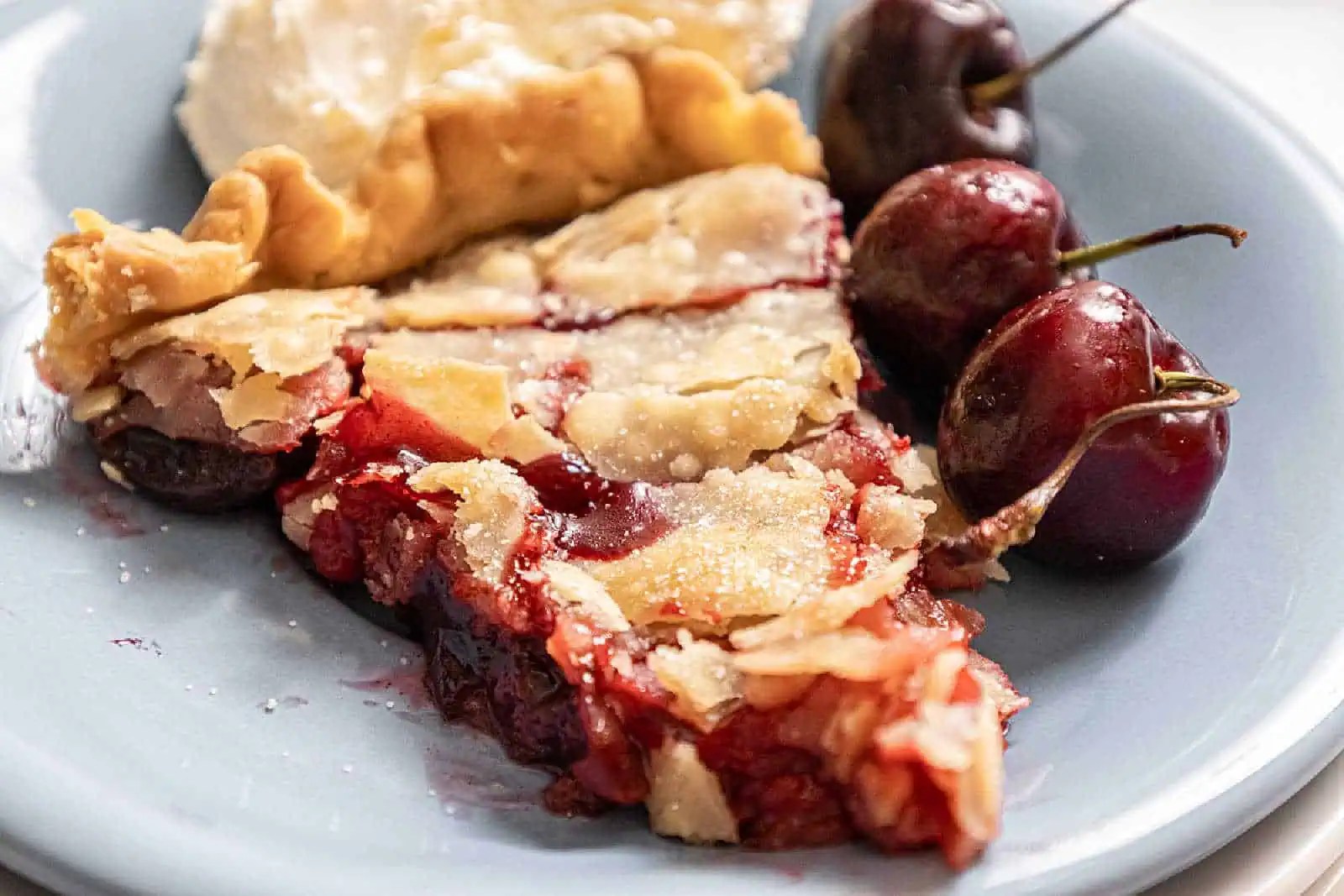 A slice of cherry pandowdy served with whole cherries on a plate.