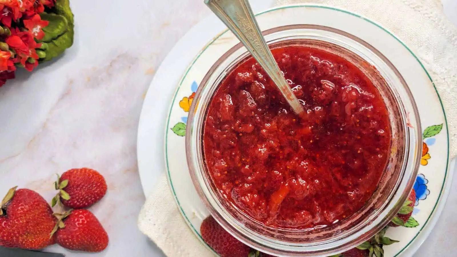 Strawberry jam in a jar on a plate.