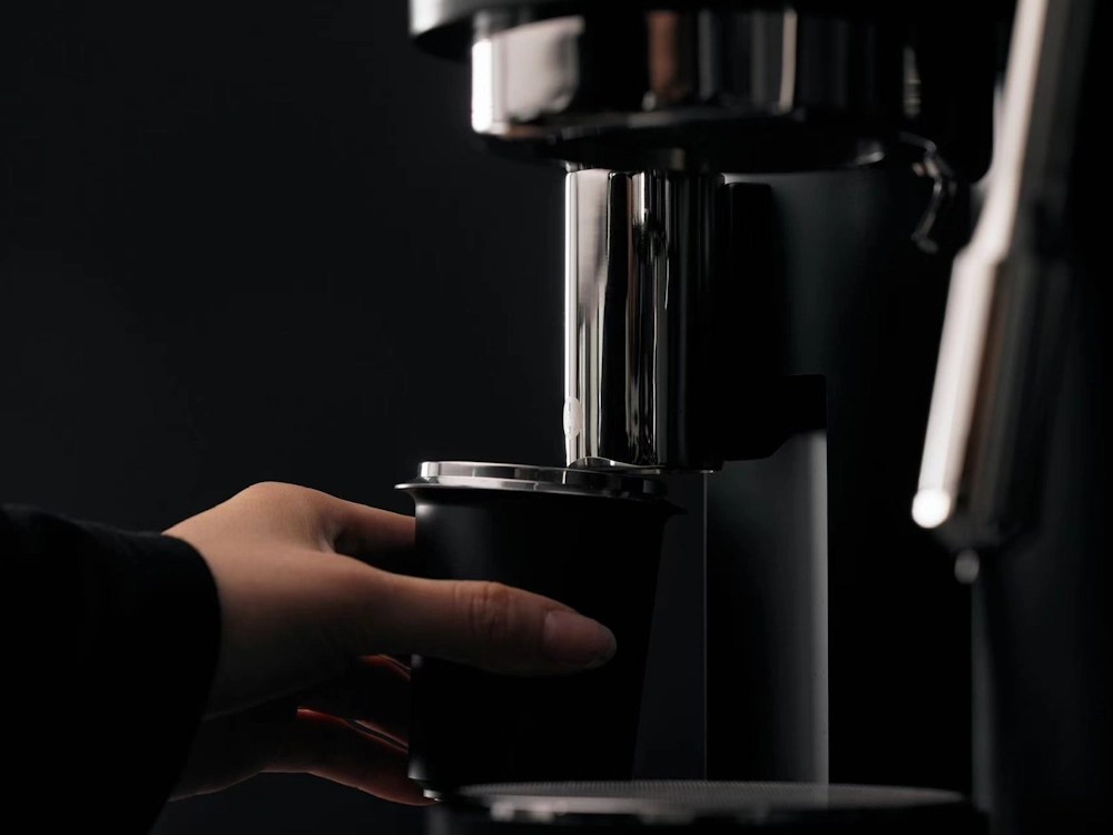 - Healthy Brew Hub A person removes the grinder dispenser cup from a coffee machine.