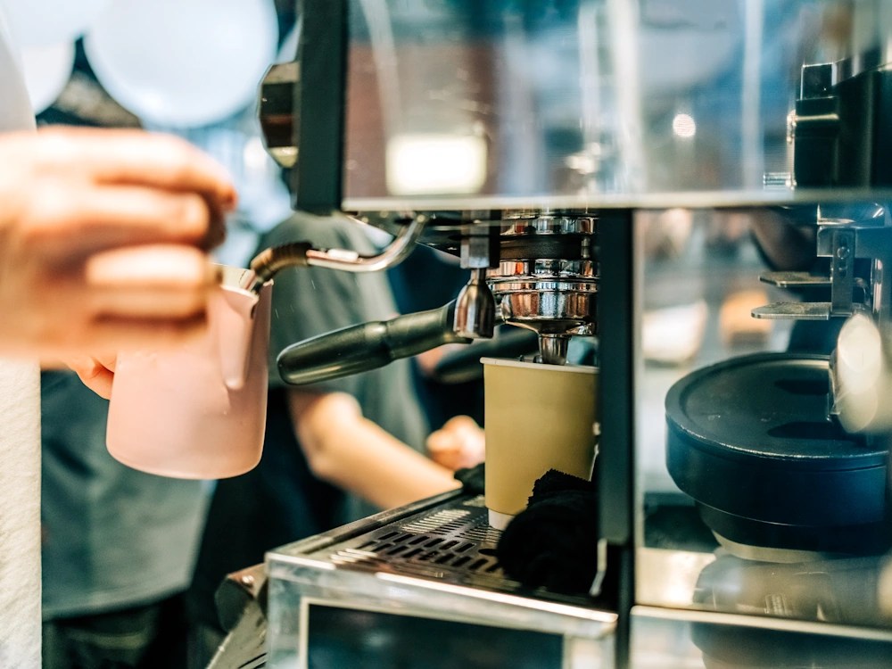 - Healthy Brew Hub A barista steams milk and extracts espresso in a café.