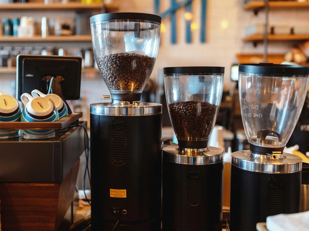 Three grinders next to an espresso machine.