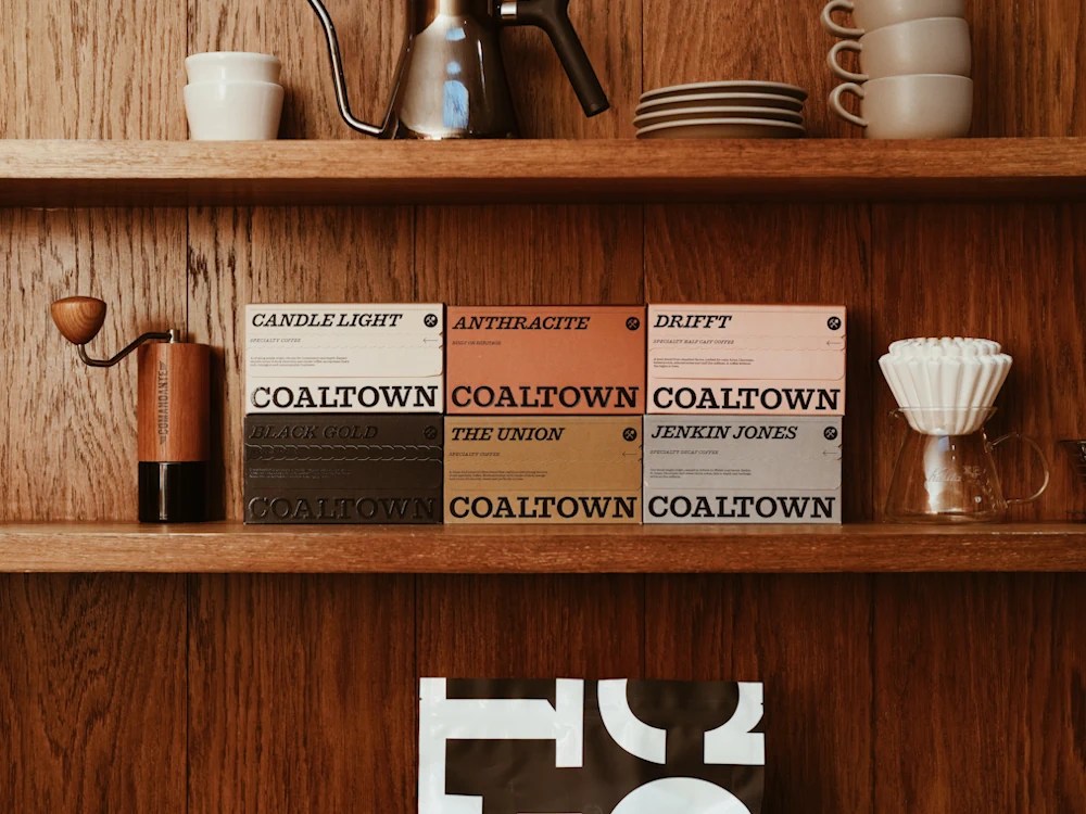 Coaltown Coffee boxes on a shelf next to brewing equipment.
