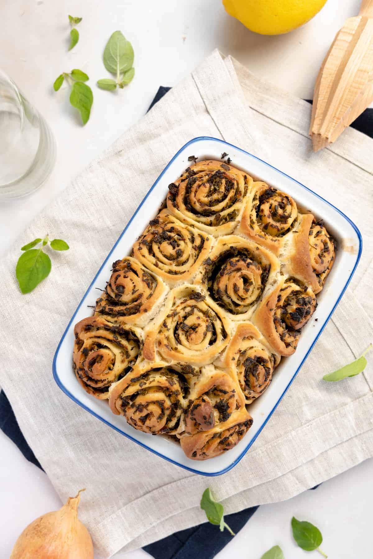 oregano bread scrolls in a white tray with a blue rim