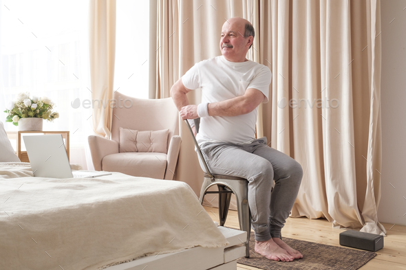 Sporty Senior Man Practicing Yoga Using Chair Doing Parivrtta Utkatasana Stock Photo By Koldunov