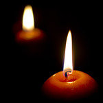 Glowing candle and its reflection in the dark