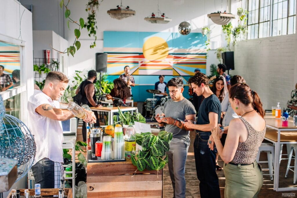 Guests gather at the bar in a brightly lit party space with a band playing in the background