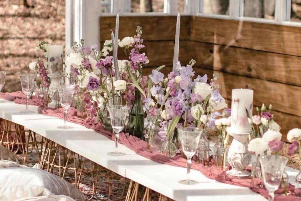 Pink and purple flowers are scattered along a long, low bohemian-inspired table