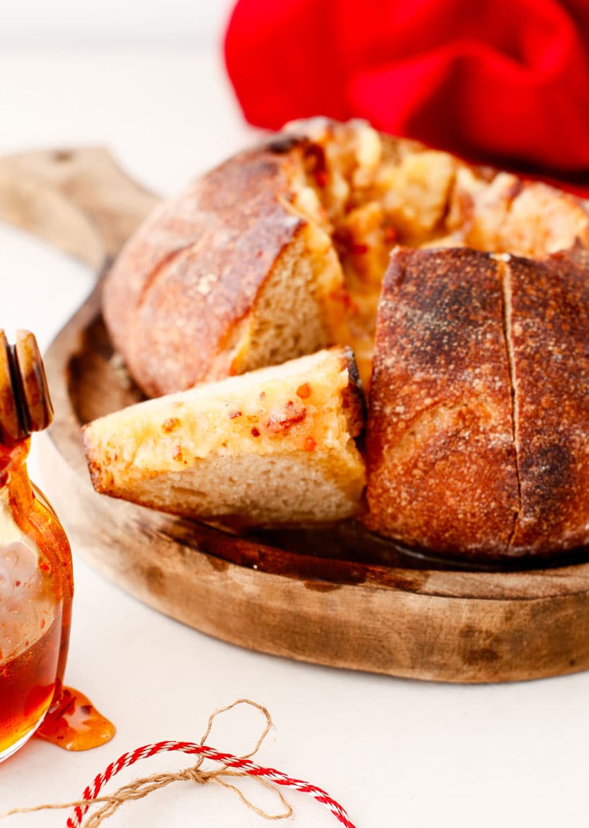 a hot honey butter coated slice of bread resting on a wooden cutting board