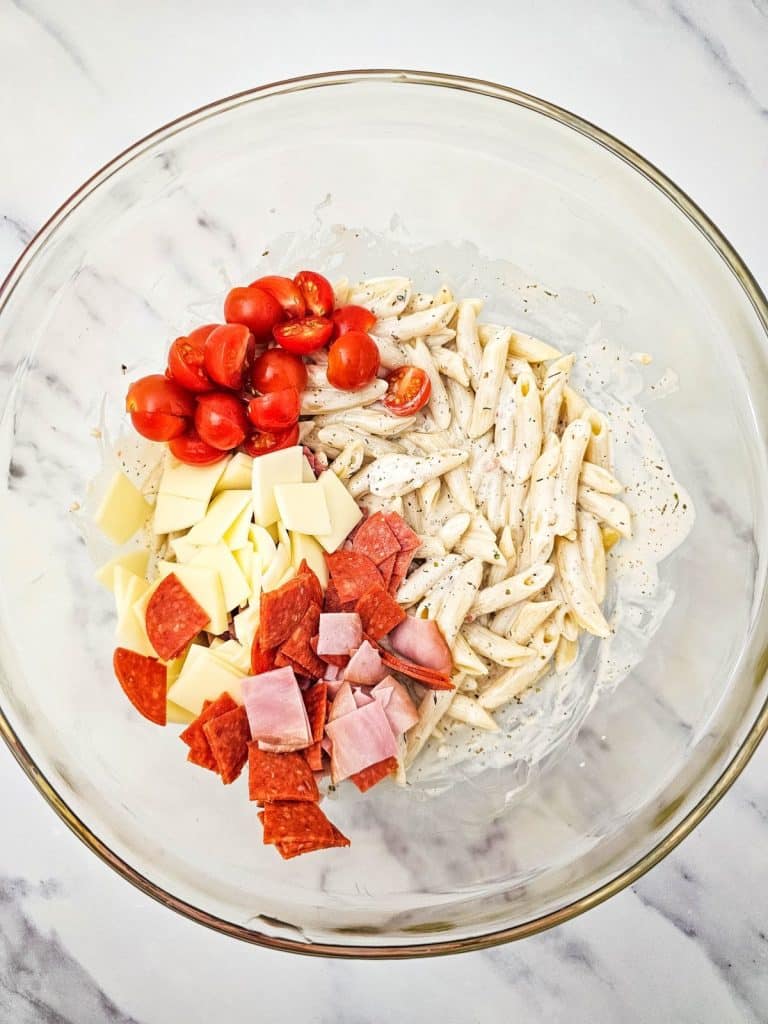 italian hoagie pasta salad ingredients in a large glass mixing bowl