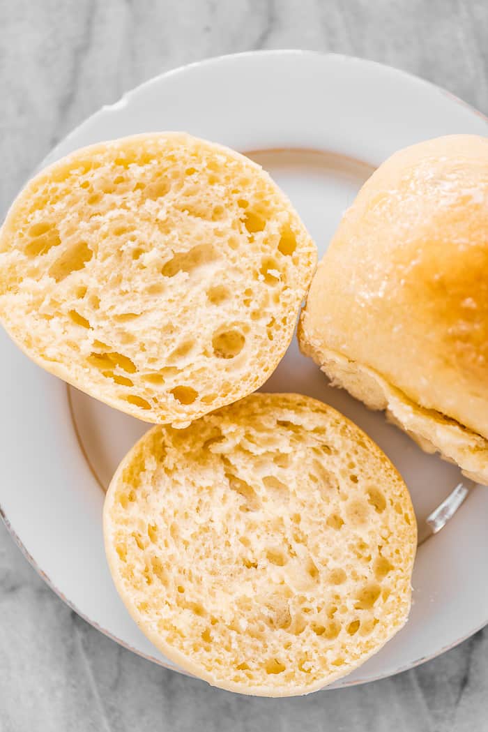 These potato rolls are light, fluffy, and absolutely delicious. They make the perfect dinner buns and are great for sandwiches and dipping into soup, too. A potato bun on a plate cut in half.