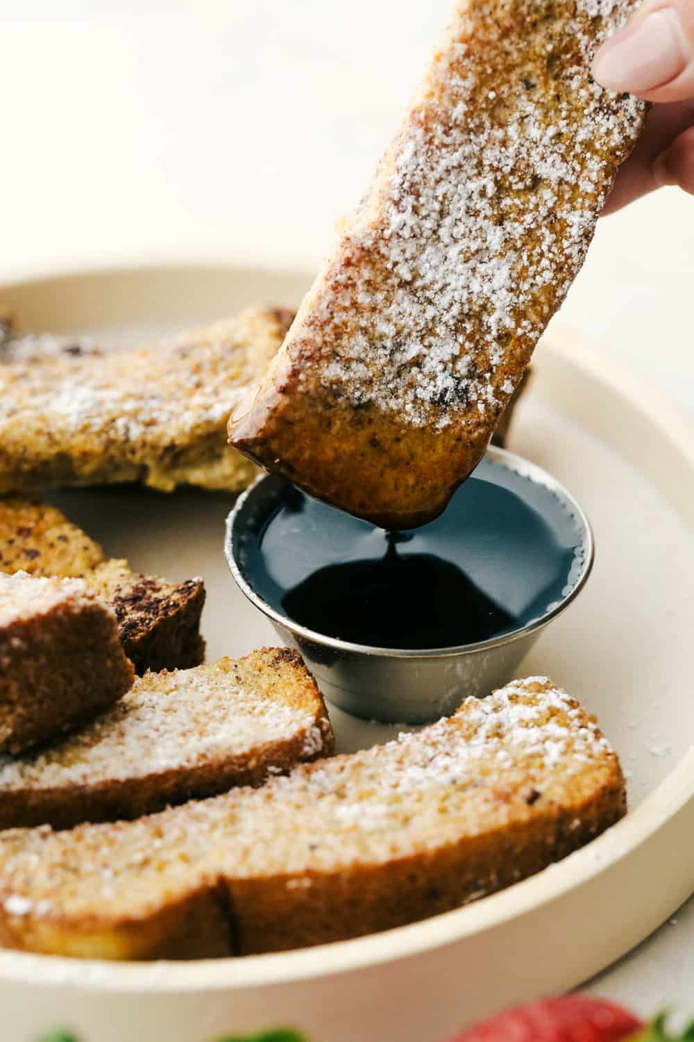 Air Fryer French Toast Sticks are a super fun fast way to make breakfast in the morning. Coated in a vanilla and cinnamon egg mixture, these fry up absolutely amazing! Dipping a french toast stick in maple syrup.