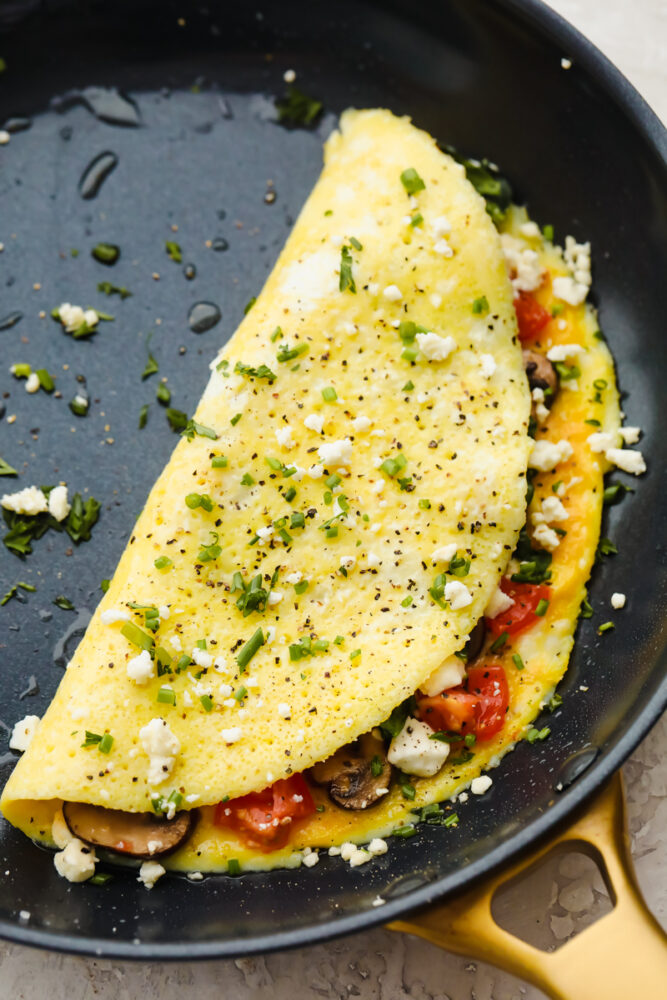 Savory breakfast omelets are so classic and my go to for a home run breakfast! Quick, easy, and delicious, this healthy breakfast option will leave you feeling full and satisfied! A cooked omelet with toppings in a pan.