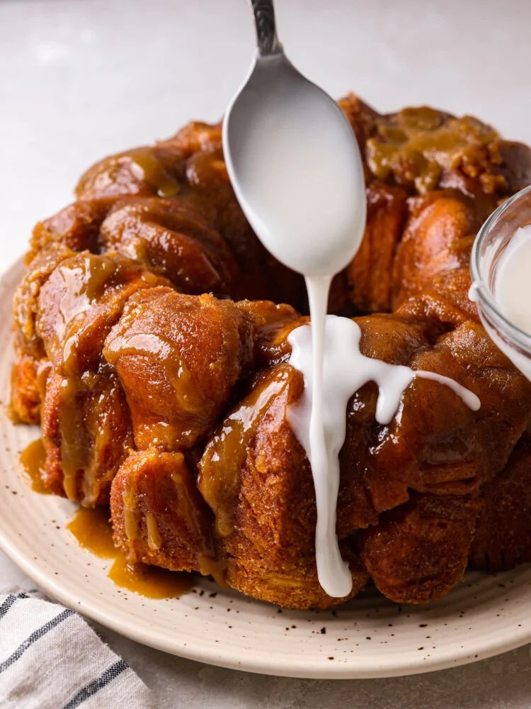 Sweet and silky Powdered Sugar Glaze is the perfect topping for your baked goods and desserts. It is so simple to make with just 3 ingredients and will be the perfect addition to your goodies! Powdered sugar glaze being drizzled on top of monkey bread.