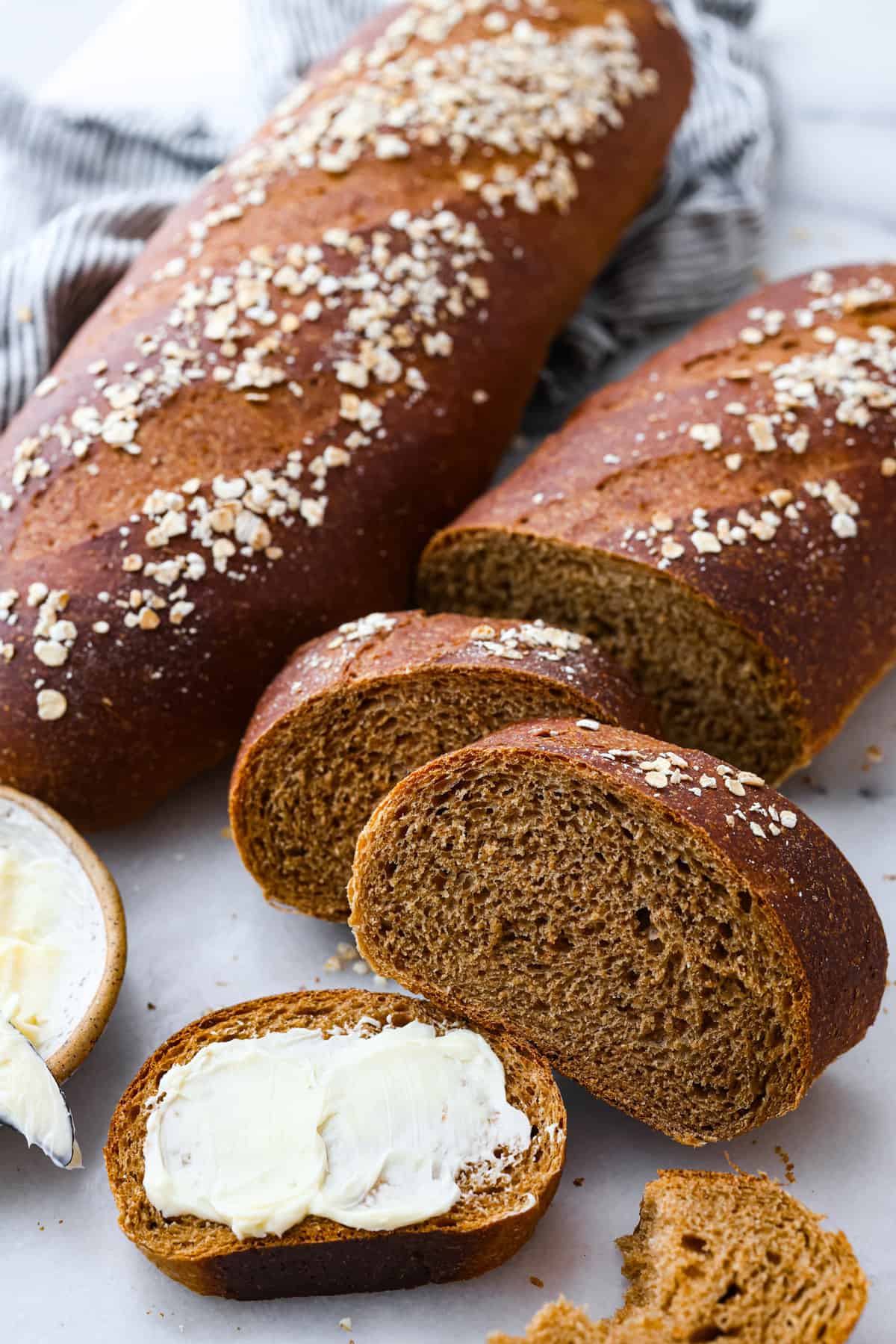 Make this copycat version of the EPIC Cheesecake Factory brown bread that is loved and devoured by all who dine at this incredible American restaurant. The rich brown color comes from the molasses, honey, whole wheat, espresso, and cocoa powder. These unique ingredients create the tastiest bread that no one can resist! Close view of baked brown bread loves. Once loaf is sliced with butter spread onto a piece of bread.