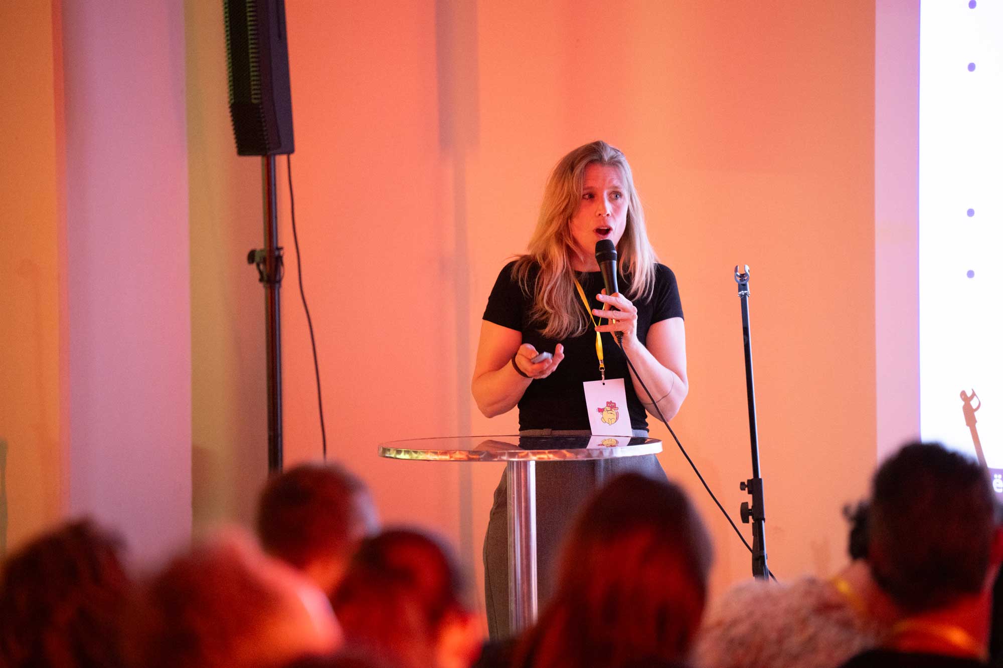 Alt Ctrl Org Draws 200+ for Open Discussion on WordPress, Free Software, and Governance 1 A woman speaks into a microphone at a podium, with an audience visible behind her.