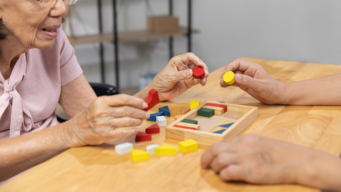 Unlocking Cognitive Health: How Genetics and Lifestyle Choices Enhance Brain Vitality in Aging Adults | University of Hawaiʻi System News 1 Caregiver and senior woman playing wooden shape puzzles game for dementia prevention