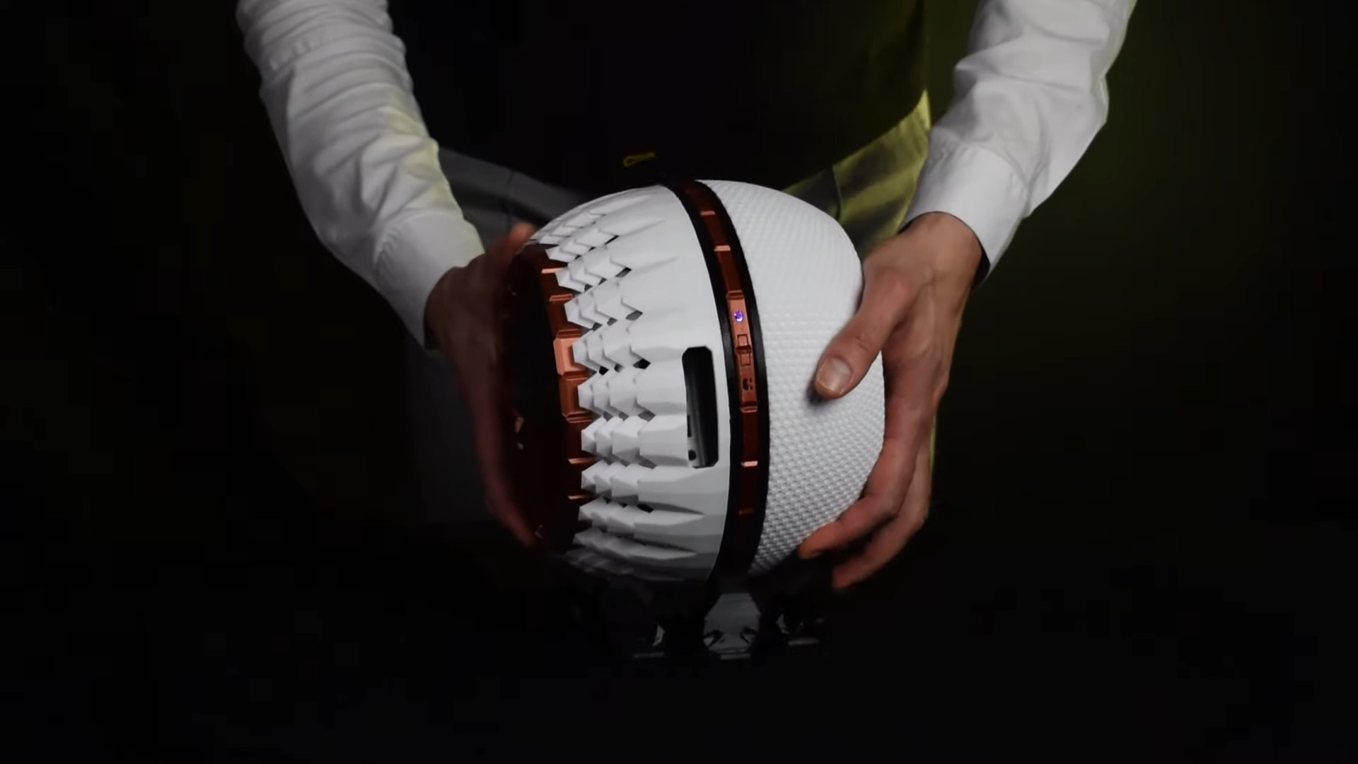 A man places a 3D printed spherical PC case on a table