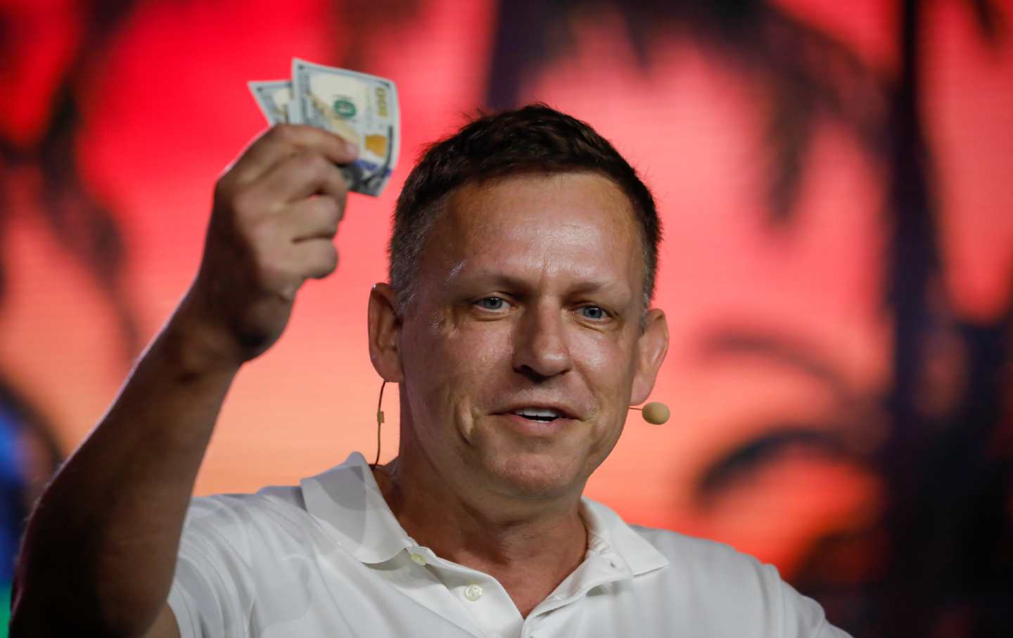 Peter Thiel brandishes $100 bills at the Bitcoin 2022 conference. (